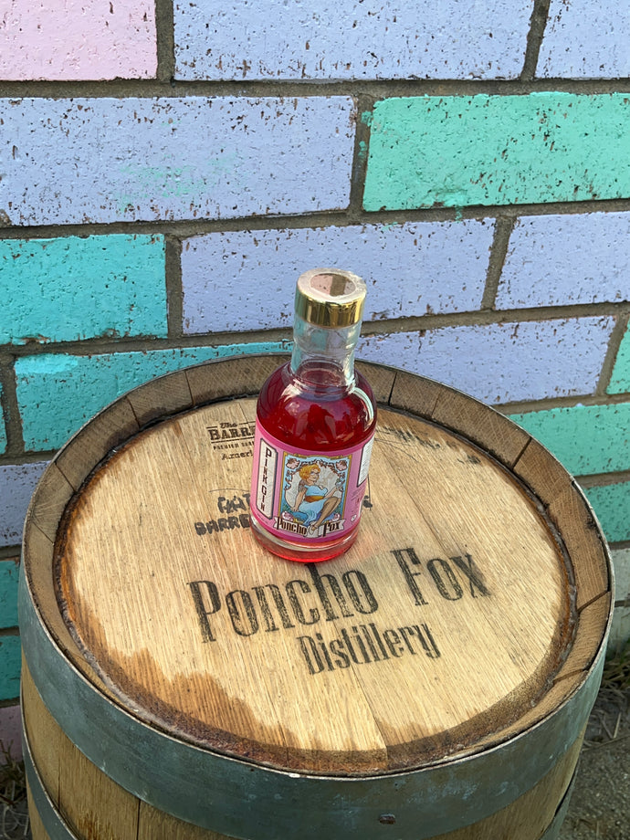 Bottle of Poncho Fox Pick Gin on a wooden barrel with colorful tiled background